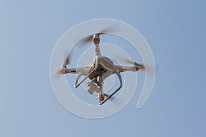 Modern RC Drone / Quadcopter with camera flying in a bright and clear blue sky. New technology in the aero photo shooting