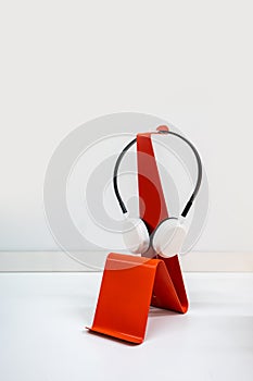 Modern red curve metal stand for wireless headset isolated on white