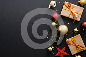 Modern red and golden Christmas decorations, baubles, gift boxes, confetti stars on dark black background. Flat lay design, top