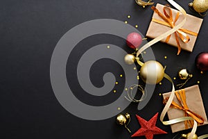 Modern red and golden Christmas decorations, baubles, gift boxes on dark black background. Flat lay design, top view, copy space.