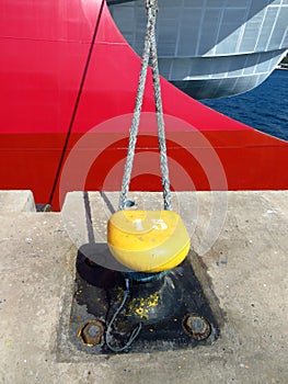 Modern red and gray ship bow. Mooring bollard with heavy duty mooring ropes. Detail of mooring with the rope of the boat in the