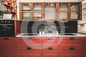 Modern red kitchen interior with black brick walls, wooden countertops with a built in sink and a cooker.