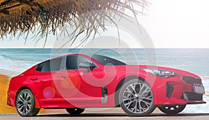 Modern red luxury car at the beach under the palm trees