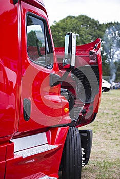 Modern red semi truck with open hood on parking lot