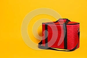 Modern red thermo bag on yellow background. Space for text