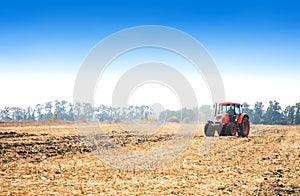 Modern red tractor in the field.