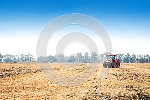 Modern red tractor in the field.