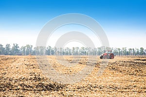 Modern red tractor in the field.