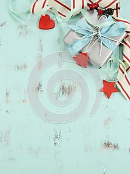 Modern red and white Christmas decorations on aqua blue wood background, with silver gift - vertical.
