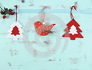 Modern red and white Christmas hanging bird and tree decorations on aqua blue wood background.