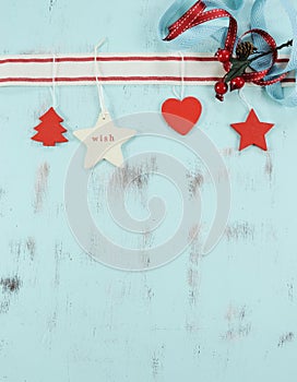 Modern red and white hanging Christmas decorations on aqua blue wood background. Vertical.