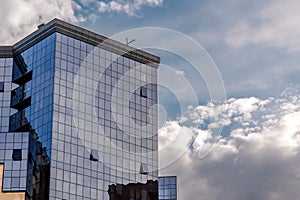 Modern reflective glass building reflects blue sky and clouds showcasing urban design