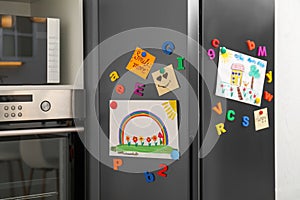 Modern refrigerator with child`s drawings, notes and magnets
