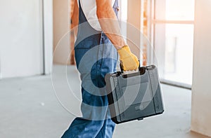 Modern repair. Young man working in uniform at construction at daytime