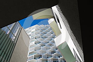 Modern residential architecture with repeating balconies and geometric facade under bright clear blue sky background