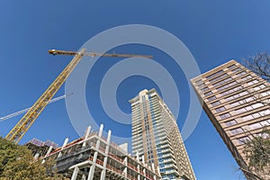 Modern residential buildings and construction crane against vibrant blue sky