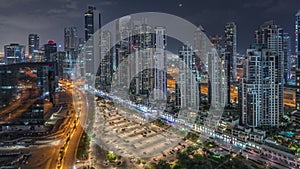 Modern residential and office complex with many towers aerial night timelapse at Business Bay, Dubai, UAE.