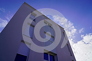 Modern residential rectangular facade of a building with apartments windows and balconies on blue sky