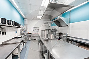 Modern restaurant kitchen with stainless steel kitchenware and equipment. Cooking with preparation tables, pans, pots