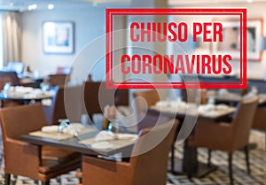 Modern restaurant with tables closed and sign in Italian saying Closed due to Coronavirus photo