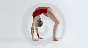 Modern rhythmic gymnastics. Flexible girl in leotard doing back bend on white background