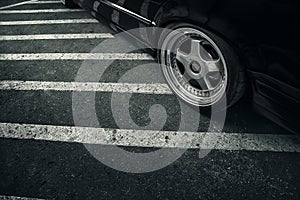 Modern rims on wheel of black car at asphalt road