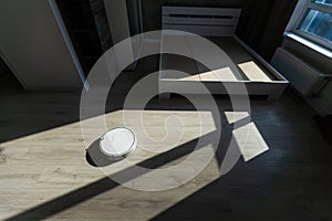 Modern robot vacuum cleaner on wooden floor in room