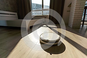 Modern robot vacuum cleaner on wooden floor in room