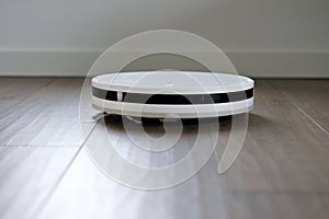 modern robot vacuum cleaner working on brown floor