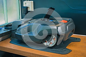 Modern robotic lawnmower being charged on a service stand in a garden charger