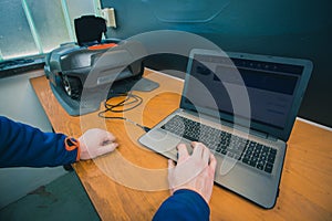 Modern robotic lawnmower being connected to a computer or laptop as part of service diagnostics and software update during annual