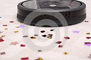 Modern robotic vacuum cleaner removing confetti from carpet. Space for text