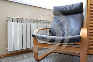 Modern rocking chair at the radiator. brown leather pillows. part of the interior of the room. coziness and comfort.