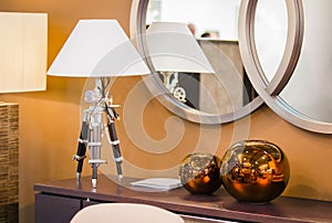 Modern room design. hest of drawers with a table lamp on a tripod, copper round decorative vases