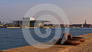 Modern royal opera house (Operaen) located at the shore of Ã˜resund in Copenhagen, Denmark with metal mooring ring.