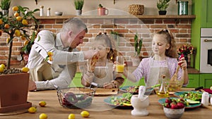 At the modern rustic kitchen island the charismatic dad together with his daughters preparing the breakfast he gives