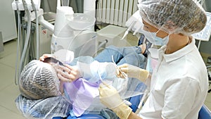 Modern safety dental clinic. Dental treatment doctor wearing plastic protective shield, Patient puts on sun glasses