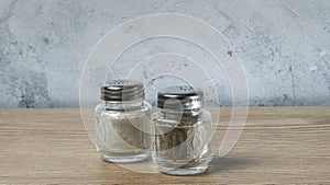 Modern Salt and Classic pepper grinders standing on wood texture table. Salt and pepper shaker on wooden board.