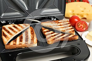 Modern sandwich maker with bread slices, closeup