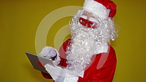 Modern Santa Claus with red glasses checking his tablet