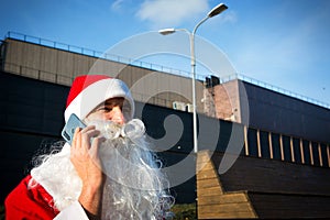 Modern Santa Claus talking on the phone. Ordering the services of an animator for the Christmas and new year. Online greetings via