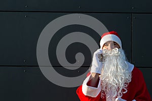 Modern Santa Claus talking on the phone. Ordering the services of an animator for the Christmas and new year. Online greetings via