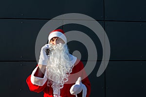 Modern Santa Claus talking on the phone. Ordering the services of an animator for the Christmas and new year. Online greetings via