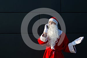 Modern Santa Claus talking on the phone. Ordering the services of an animator for the Christmas and new year. Online greetings via