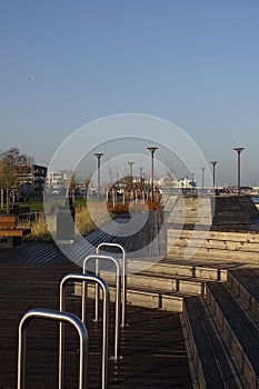Modern scape in the city. Wooden constractions. Metal steel handrails in the front. Wooden deck and many lamposts in the