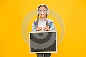 Modern school life. Schoolgirl pupil informing you. School girl hold blank chalkboard copy space. Announcement and photo