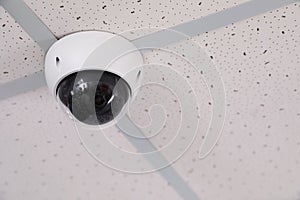 Modern security CCTV camera on ceiling in office. Protection system
