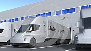 Modern semi-trailer trucks with MADE IN BRAZIL text being loaded or unloaded at warehouse. Brazilian business related