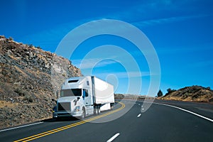 Modern semi truck and trailer on turning rocky windy road