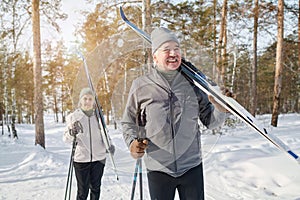 Modern Senior Couple Carrying Skis And Poles